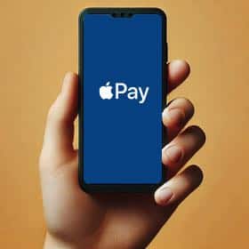 En person håller i en mobil där det står Apple Pay på skärmen.